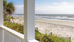 A beach view with a wooden fence and a palm tree.