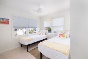 Un dormitorio con dos camas, ventilador de techo y vistas al exterior.