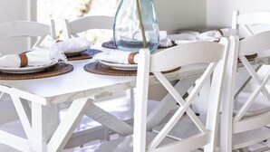 A dining area with a chandelier, white chairs, and a table set for two.