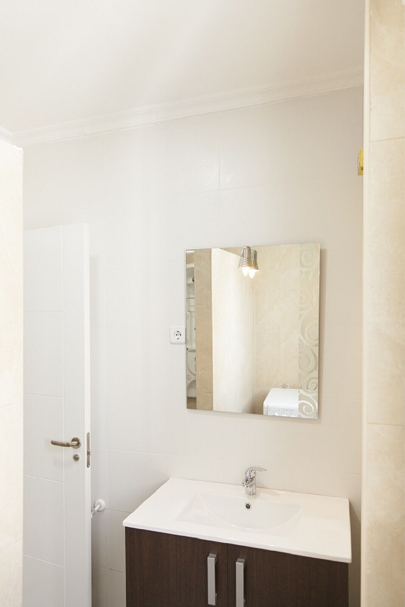 Un baño con lavamanos blanco, espejo y zona de ducha.
