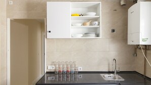 A kitchen with a black countertop, a white cabinet with dishes, and a water dispenser.
