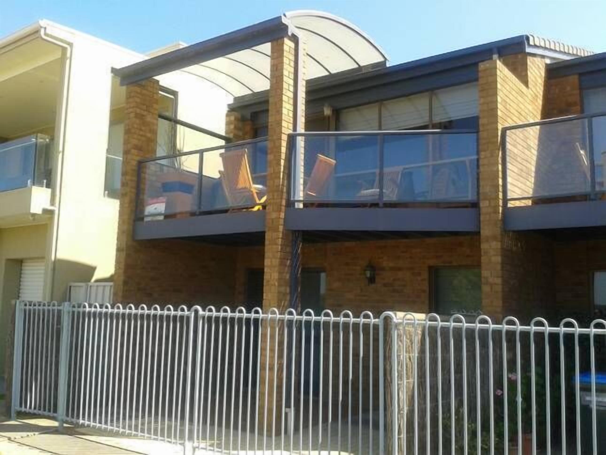 Un edificio moderno de dos pisos con un balcón de vidrio en el nivel superior.