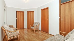 A room with three wooden doors, a wicker chair, and a sofa.