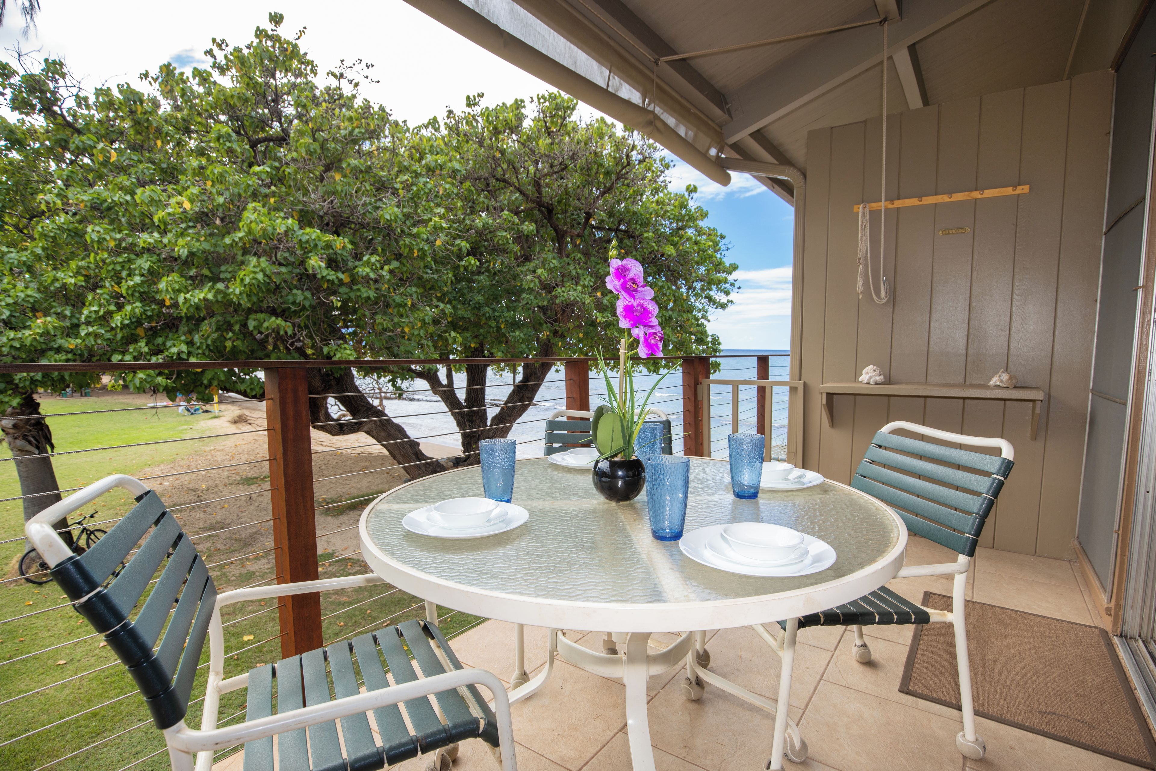 A round table with chairs, a vase with flowers, and a view of the sea.