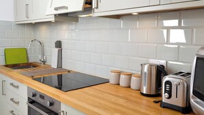 Eine moderne Küche mit weißen Schränken, einer Holz Arbeitsplatte, einer Spüle, einem Wasserkocher, einem Toaster und einem Herd.