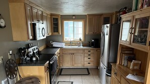 A kitchen with wooden cabinets, a stove, a refrigerator, and a window.