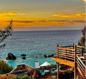 A coastal view with a wooden deck, outdoor seating, and a view of the sea. - "Two Hearts" NEW Suite at #5 Cross Bay Private Estate & Beach, starting at 150 (Southampton)
