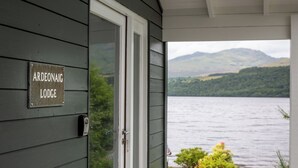 En dør med et skilt, der siger "Ardeonaig Lodge", og udsigt til en sø med bjerge i baggrunden.