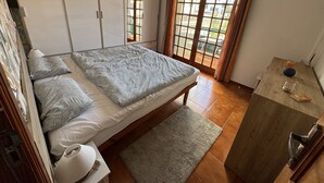 A bedroom with a bed, a nightstand, a dresser, and a window with curtains.