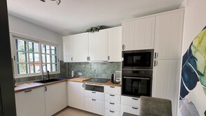 A modern kitchen with white cabinets, a built-in oven, microwave, and dishwasher.