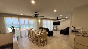 A spacious living area with a dining table, sofas, and a TV. - Newly Renovated Ocean View White Sand Beachfront 3 Bed 3 Bath Two Level Condo (Cancún)