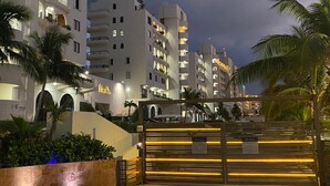 A multi-story hotel with balconies and a well-lit entrance. - Newly Renovated Ocean View White Sand Beachfront 3 Bed 3 Bath Two Level Condo (Cancún)