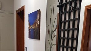 Een gang met een betegelde vloer, een zwarte console tafel, een decoratieve wand en een ingelijst kunstwerk aan de muur.