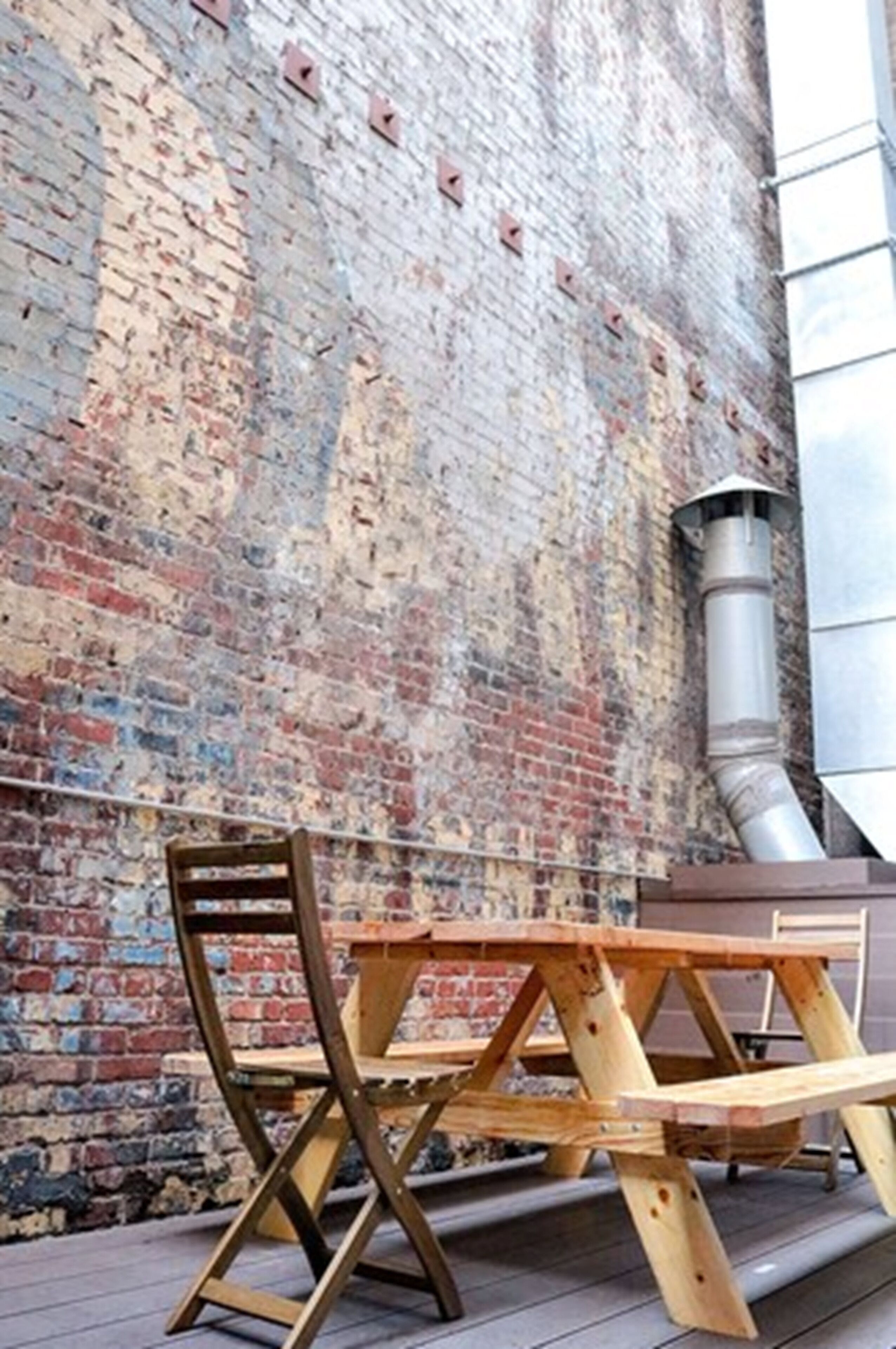 A picnic table and chair set against a brick wall.