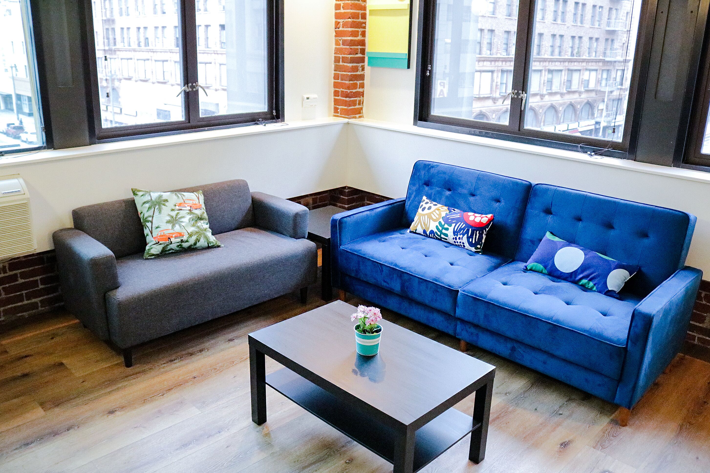A living room with a grey sofa, a blue sofa, and a coffee table with a flower vase.