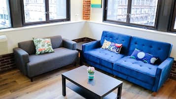 A living room with a grey sofa, a blue sofa, and a coffee table with a flower vase.
