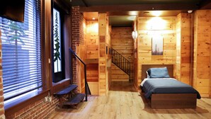A wooden cabin-style room with a bed, a bench, and a staircase leading to another room. - The Haas, Trademark Collection by Wyndham (Los Angeles)