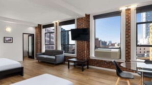 A modern hotel room with a large window, a flat-screen TV, a sofa, a small table, and a bed. - The Haas, Trademark Collection by Wyndham (Los Angeles)