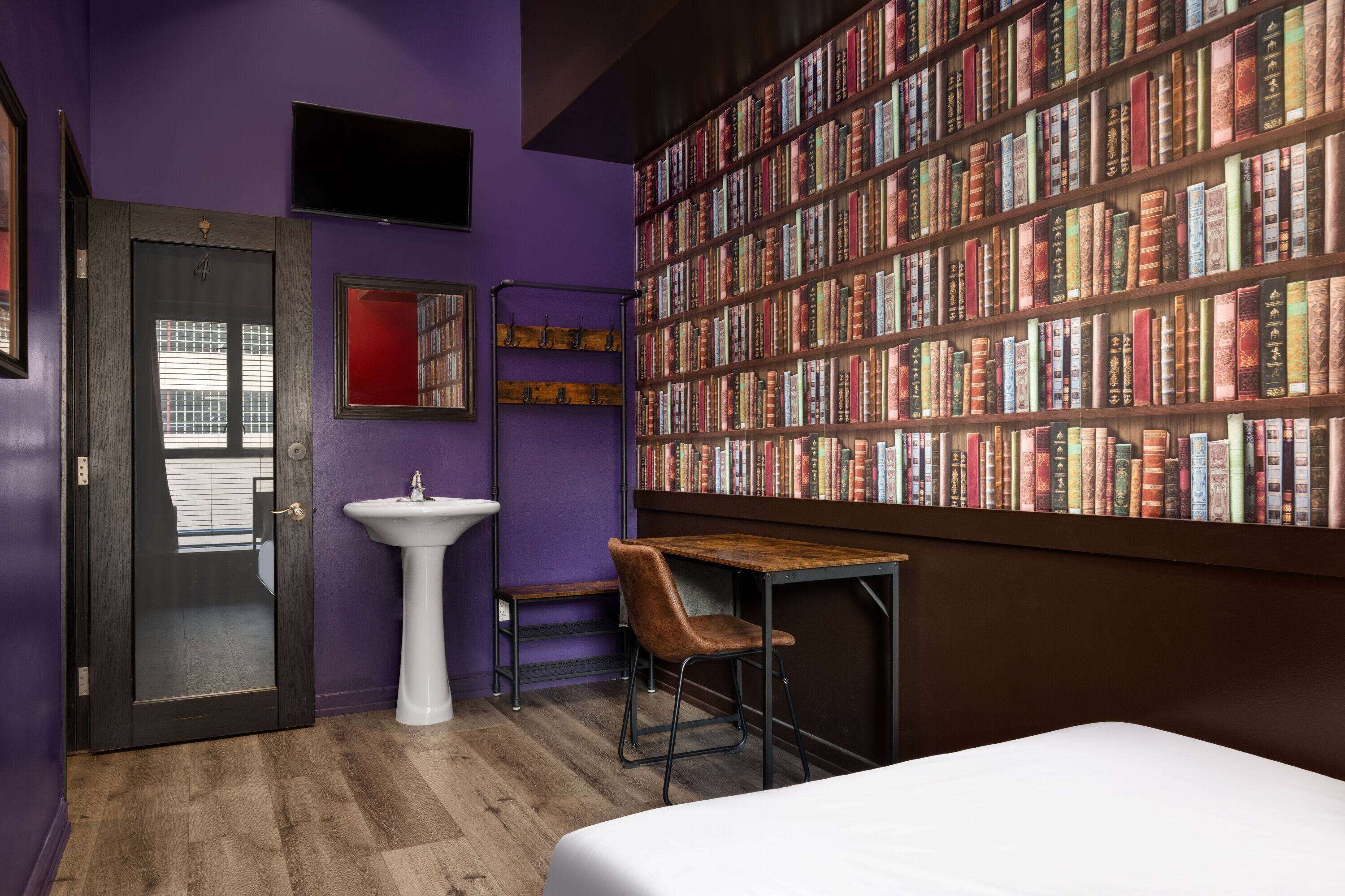 Une pièce comprenant un lit, un bureau, une chaise, une bibliothèque, un lavabo et une porte.
