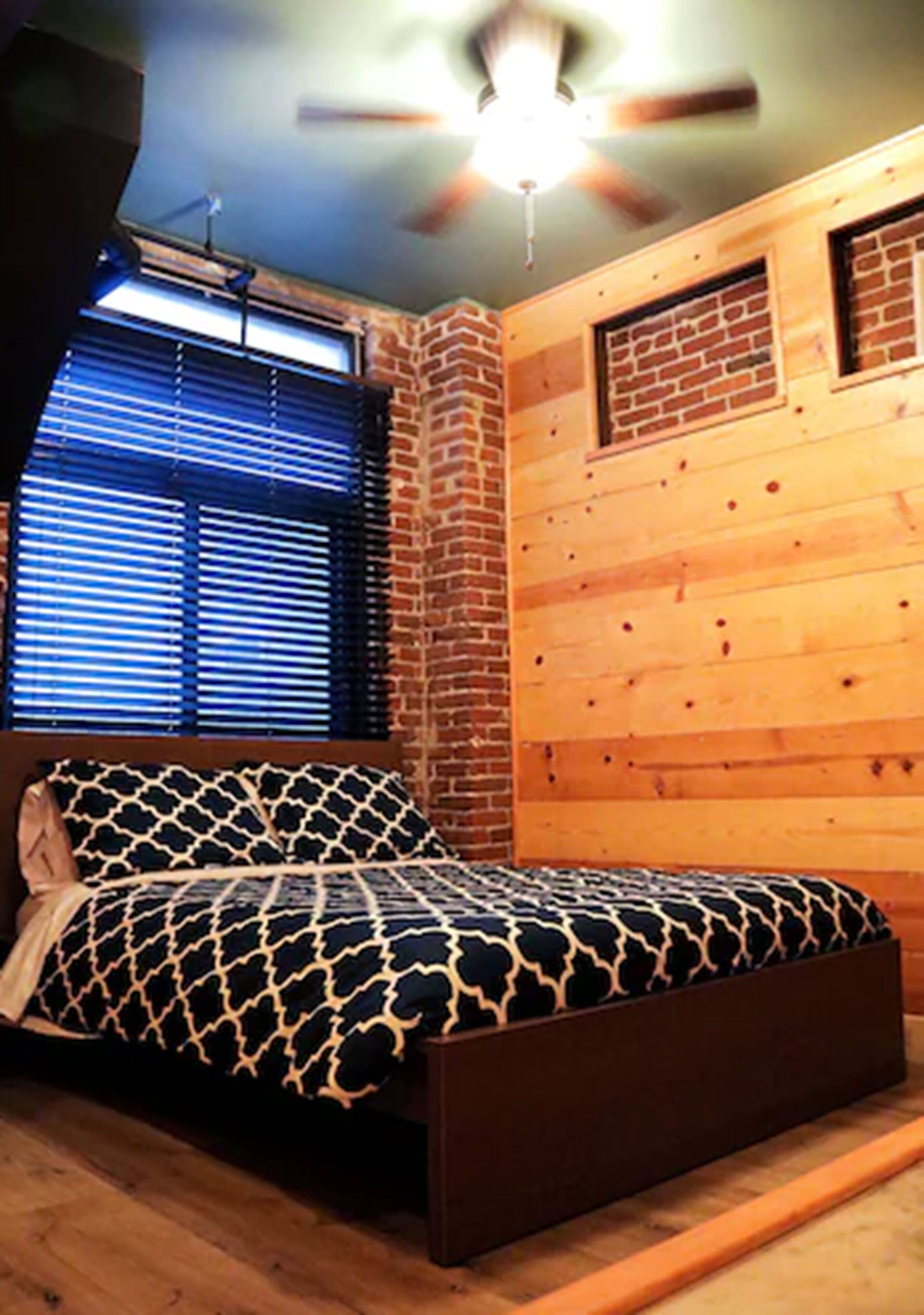 A bedroom with a bed, a ceiling fan, and a window with blinds.