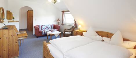 A cozy bedroom with a large bed, wooden furniture, a small table, and a chair.