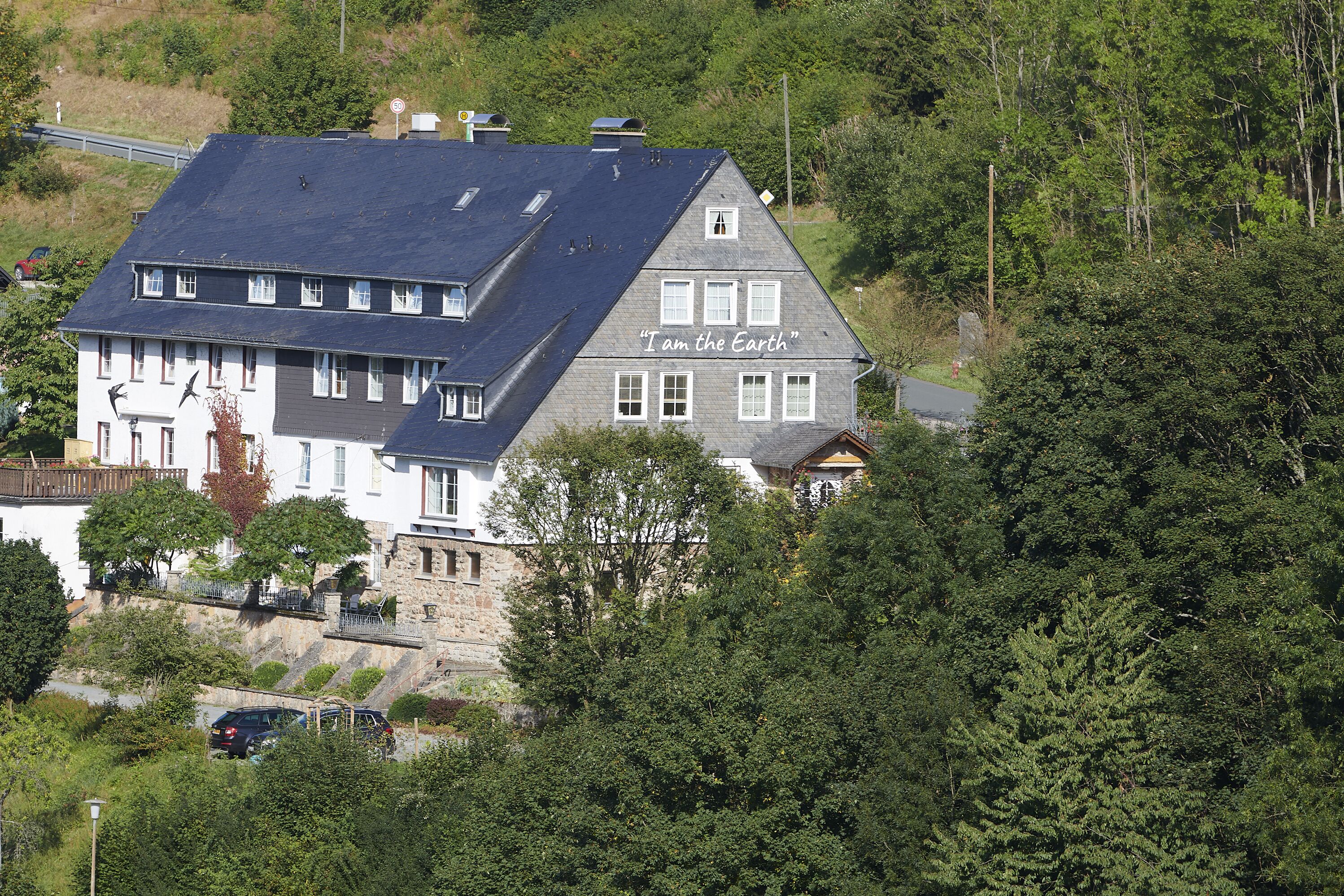A two-story building with a sloped roof and a sign that reads "I am the Earth."