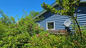 A blue house with a white window and a white bell-shaped object on the porch.