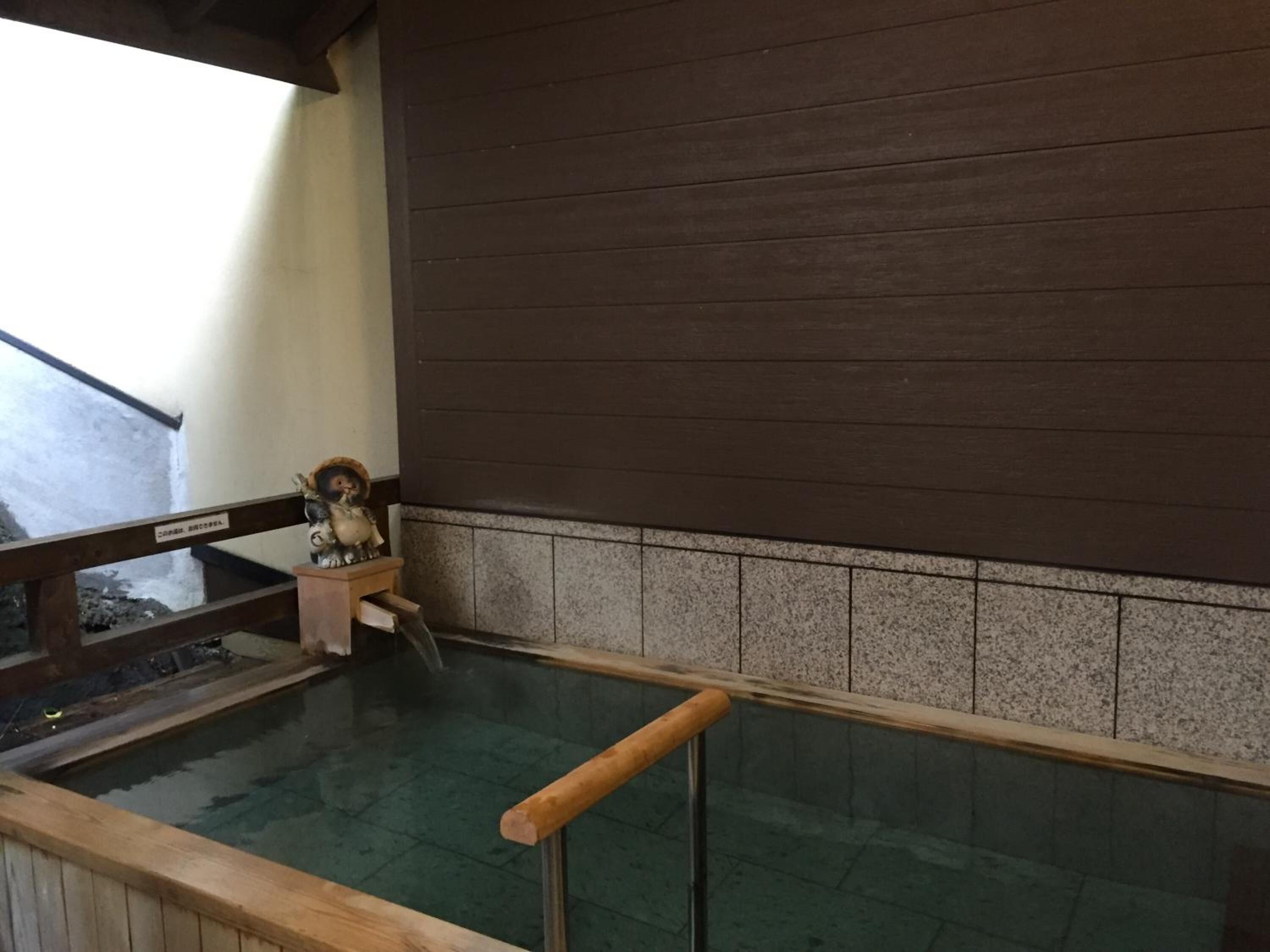 A wooden deck with a railing overlooking a pool area.