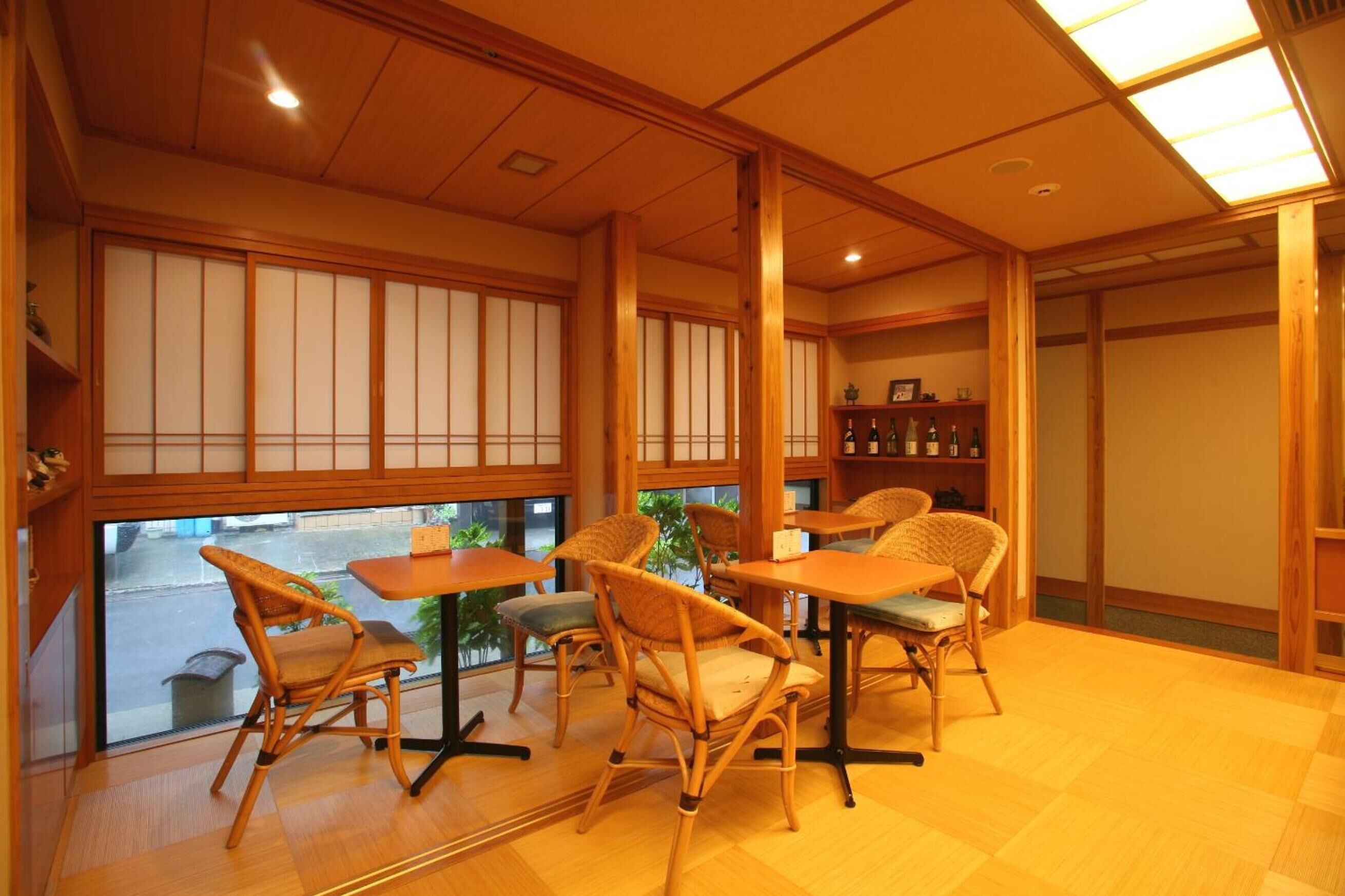 A traditional Japanese room with tatami flooring, low wooden tables, and woven chairs.