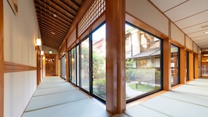 Ein Korridor mit Tatami-Bodenbelag und großen Fenstern.