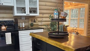 A kitchen with wooden cabinets, a black stove, and a wooden island with baskets.