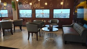A coffee-themed lounge with seating, large windows, and a view of the cityscape.