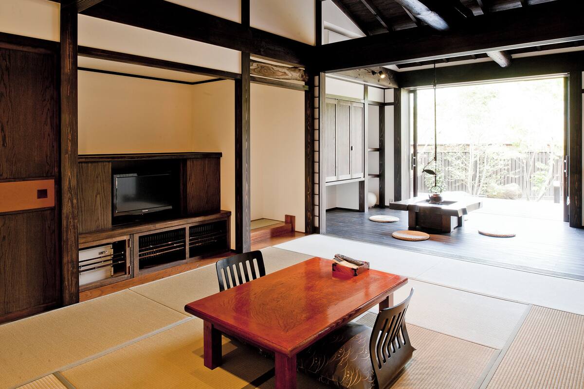 A traditional Japanese-style room with tatami flooring, a low wooden table, and a television set.