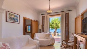 Ein Zimmer mit Bett, einer Schlafcouch, einem Schaukelstuhl, einem Fernseher und Meerblick.