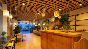 A wooden reception desk with a counter, wooden chairs, and tables arranged in a cafe-style setting. - An Thai Bar & Homestay (Hoa Lu)