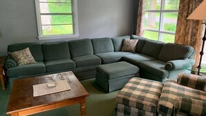 Una sala de estar con un sofá modular, una mesa de centro de madera y un reposapiés escocés.