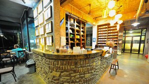 A stone counter with a wooden interior, shelves with various items, and a guitar in the background.