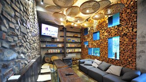 A cozy interior with a stone wall, wooden benches, a sofa, and a fireplace.
