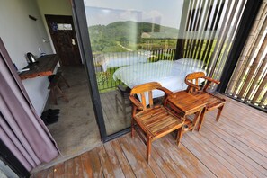 A balcony with a bed, wooden chairs, and a table. - Yangshuo Sudder Street Guesthouse (Guilin)