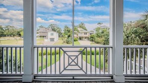 Eine Veranda mit Blick auf eine Wohngegend, mit symmetrischem Design, weißen Geländern und einem zentralen Ziertelement.