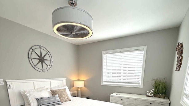 Ein Schlafzimmer mit Bett, Nachttisch, Lampe, Fenster und Wanddekoration.