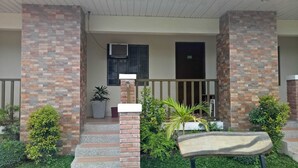 A hotel entrance with a brick facade, a small porch with steps, a potted plant, and a bench. - Hacienda Galea Resort and Events Place (Baliuag)