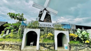 A traditional windmill with a sign reading "ACIENDA G" in front. There are two arched entrances below the windmill. - Hacienda Galea Resort and Events Place (Baliuag)