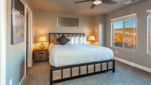 A bedroom with a bed, bedside lamps, a ceiling fan, and a window with a view. - Poolside 4 bdr near OHV Trails w/ Game Room (Washington)