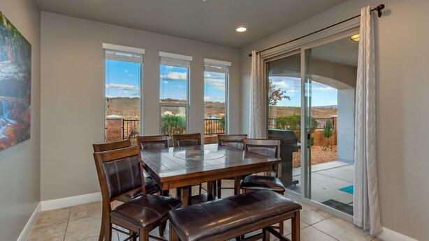 A dining area with a large table and chairs, a view of the desert through large windows, and a sliding glass door leading to an outdoor patio. - Poolside 4 bdr near OHV Trails w/ Game Room (Washington)