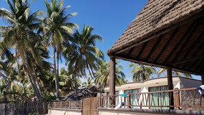 A beachside resort with thatched-roof structures, palm trees, and a sandy beach. - La Perla Playa Azul Bungalow #1 (Playa Azul)