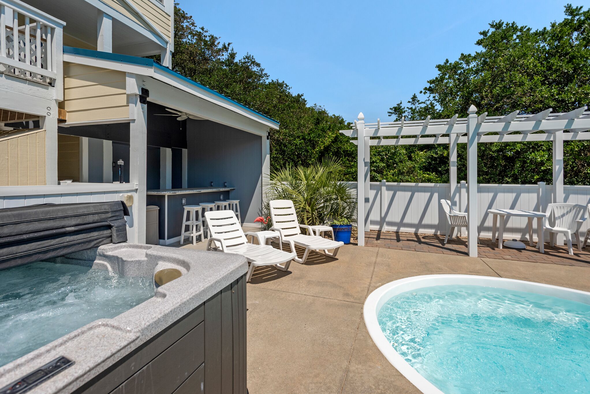 A pool area with a hot tub, lounge chairs, and a pergola.