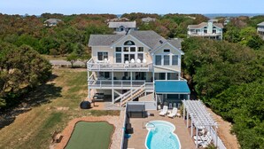 A large house with a swimming pool, a tennis court, and a boat dock. - Shell's Shack: Oceanside, Private Pool, Hot Tub, Tiki Bar, Putting Green (Corolla)