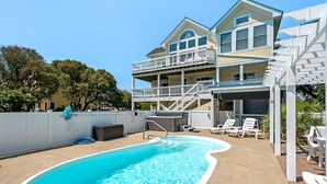 A two-story building with a pool area, including a hot tub and lounge chairs. - Shell's Shack: Oceanside, Private Pool, Hot Tub, Tiki Bar, Putting Green (Corolla)