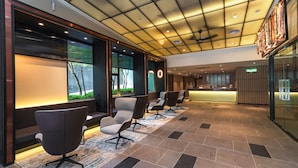A modern hotel lobby with a reception desk, seating area, and a ceiling with recessed lighting.